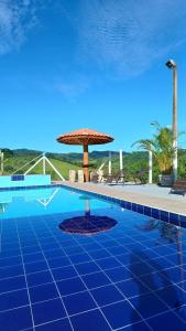 una gran piscina con sombrilla y un patio en Pousada irmãos Oliveira, en Lindóia