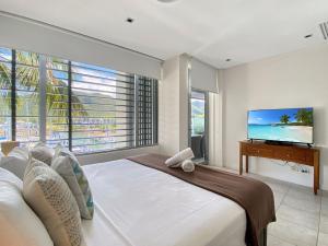 a bedroom with a large bed and a flat screen tv at Blue on Blue Penthouse Apartment 335 in Nelly Bay