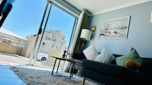 a living room with a couch and a large window at Caline Vip Apartments, beach close in Bloubergstrand