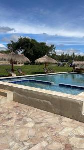 einen Pool mit zwei Strohschirmen und -stühlen in der Unterkunft Residencia Piri in Piribebuy