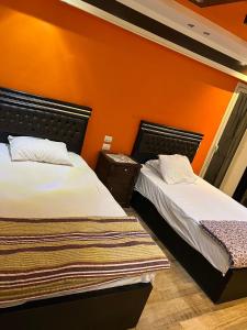 2 łóżka w pokoju z pomarańczową ścianą w obiekcie شقة فندقية على النيل مباشر بالمعادى ٣ غرف ٣ حمام w Kairze