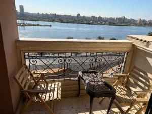 een balkon met 2 stoelen en uitzicht op het water bij شقة فندقية على النيل مباشر بالمعادى ٣ غرف ٣ حمام in Caïro