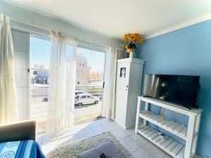 a living room with a tv and a large window at Caline Vip Apartments, beach close in Bloubergstrand