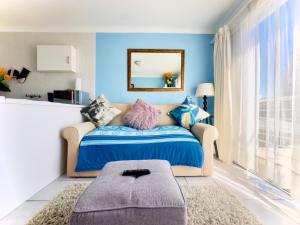 a bedroom with a bed with blue walls and a mirror at Caline Vip Apartments, beach close in Bloubergstrand