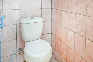 a white toilet in a bathroom with pink tiles at Cigadog Residence Mitra Reddoorz in Ciwidey