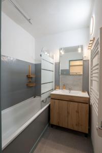 ein Badezimmer mit einem Waschbecken, einer Badewanne und einem Spiegel in der Unterkunft Pretty ski nest in the city center in Gérardmer