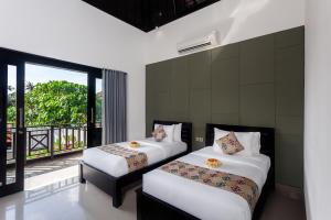 zwei Betten in einem Zimmer mit Balkon in der Unterkunft Maja Villa Batubelig by Pramana Villas in Canggu