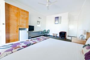 1 dormitorio con 1 cama blanca y cocina en Landsborough Lodge Motel, en Barcaldine