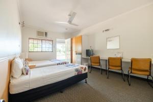 1 dormitorio con 2 camas, mesa y sillas en Landsborough Lodge Motel en Barcaldine