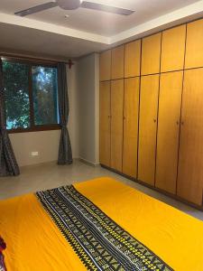 a bedroom with a yellow bed and wooden cabinets at Zanzibar in Dar! A newly renovated 3br villa in Dar es Salaam
