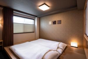 1 dormitorio con cama blanca y ventana en Rinn Kyoto Station West, en Kioto