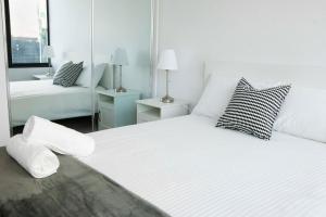 a white bedroom with two beds and a mirror at Pars apartments - Melbourne Quarter- unique View of city and Yarra in Melbourne