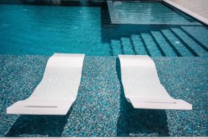 a pool with two white chairs in the water at Apartments Antique in Ulcinj