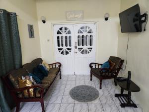 a living room with two chairs and a tv and a door at Sun Lover's Apartments in The Lime