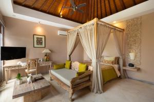 a bedroom with a canopy bed and a couch at The Royal Purnama - Adults Only in Sukawati