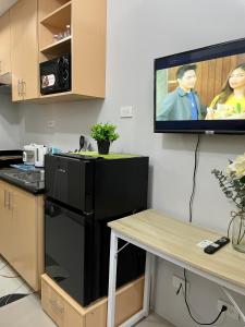 een keuken met een zwarte koelkast en een tv aan de muur bij The Grass Residences in Manilla