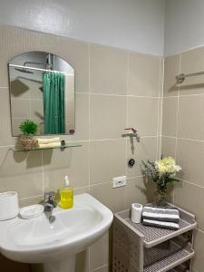 een badkamer met een wastafel en een spiegel bij The Grass Residences in Manilla