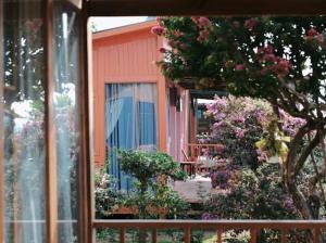 uma vista para uma casa a partir de uma janela com flores em KMI Homestay – Tea and Coffee em Di Linh