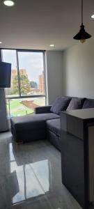 een woonkamer met een bank en een groot raam bij Disfruta de Comodidad y Tranquilidad in Bogota