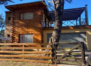 a wooden fence in front of a log cabin at Cabaña en La Caleta in Mar de Cobo
