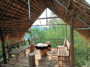 a wooden deck with benches and a table and a tree stump at Mường Trai Homestay in Sơn La