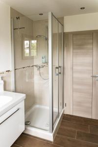 La salle de bains est pourvue d'une douche avec une porte en verre. dans l'établissement Gästehaus Sattlerhof, à Bernau am Chiemsee