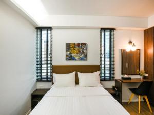 a bedroom with a large white bed and a desk at Kitzio House Hotel Huai Kwang in Ban Na Song