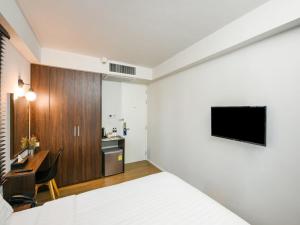 a bedroom with a bed and a desk and a television at Kitzio House Hotel Huai Kwang in Ban Na Song
