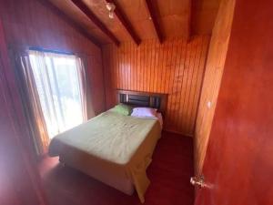a small bedroom with a bed and a window at Cabañas maule in Coronel