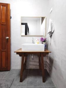 La salle de bains est pourvue d'un lavabo blanc et d'un miroir. dans l'établissement Wichouda Cottage, à Chiang Dao