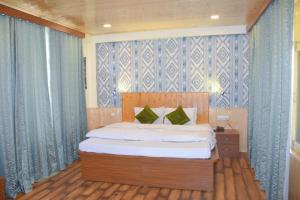 a bedroom with a large bed with blue curtains at Hotel Seraj International , Aleo Hill View in Manāli