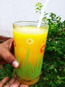a hand holding a glass of orange juice with a white straw at Venora Hiriketiya in Dickwella