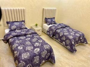 2 Betten in einem Schlafzimmer mit lila Daunendecke in der Unterkunft Appartement pour famille avec enfant in Al Hoceïma