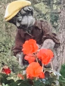a statue of a person sitting next to red flowers at Happy House Bungalov Three-Room SPA JAKUZİ Lake view in Sapanca B2 in Sapanca