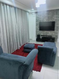 a living room with two chairs and a flat screen tv at Sommy's place in Abuja