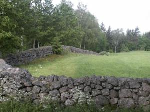 una pared de piedra frente a un campo en Idyllisches Bauernhaus in Småland, en Kättilstorp
