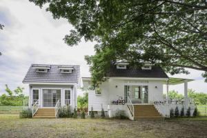 a white house with a porch and stairs at Chaisathan Cottage in Ban Ton Chok