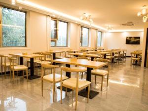 een restaurant met houten tafels, stoelen en ramen bij Green Tree Inn Beijing Daxing District Jiugong Hospital in Hongxing