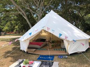 biały namiot z łóżkiem w trawie w obiekcie Glamping kaki singapore-Standard medium bell tent w Singapurze