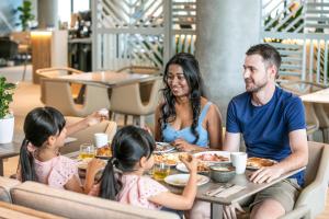 a family sitting at a table eating food at a restaurant at Holiday Inn Express & Suites Sunshine Coast, an IHG Hotel in Maroochydore