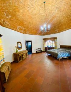 um quarto amplo com uma cama e um tecto de madeira em Casa estilo Campirano Jardín de los Soles em Taxco de Alarcón