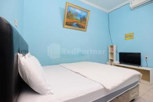 a blue room with a bed and a tv at Fajar Inn Mitra RedDoorz in Jakarta +25 photos