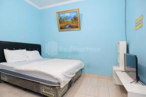 a blue room with a bed and a television at Fajar Inn Mitra RedDoorz in Jakarta