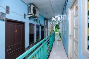 a corridor of a building with blue walls and a door at Fajar Inn Mitra RedDoorz in Jakarta