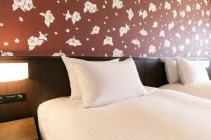 two beds in a hotel room with white sheets at Grand Mercure Okinawa Cape Zanpa Resort in Yomitan