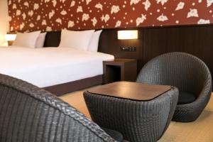 a hotel room with a bed and two chairs and a table at Grand Mercure Okinawa Cape Zanpa Resort in Yomitan