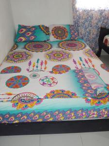 a bed with a colorful comforter on it at Mágica Cabaña familiar cerca al mar in Coveñas