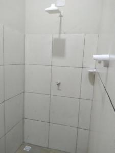 ein Bad mit einer Dusche und weiß gefliesten Wänden in der Unterkunft Yanne chalé 1 in Barra Grande