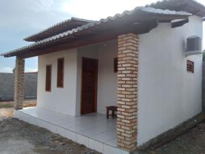 a small white house with a wooden door at Yanne chalé 1 in Barra Grande