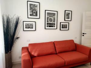 a red couch in a living room with pictures on the wall at Foresteria Juvarra in Mantova +19 photos